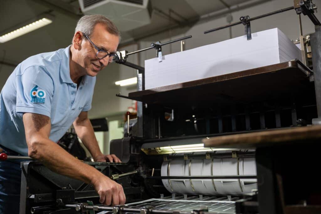 Zimmermann Druck Mitarbeiter bedient eine Druckmaschine in einer Druckerei.